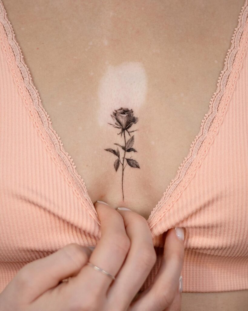 Realistic shaded rose sternum tattoo symbolizing love and resilience