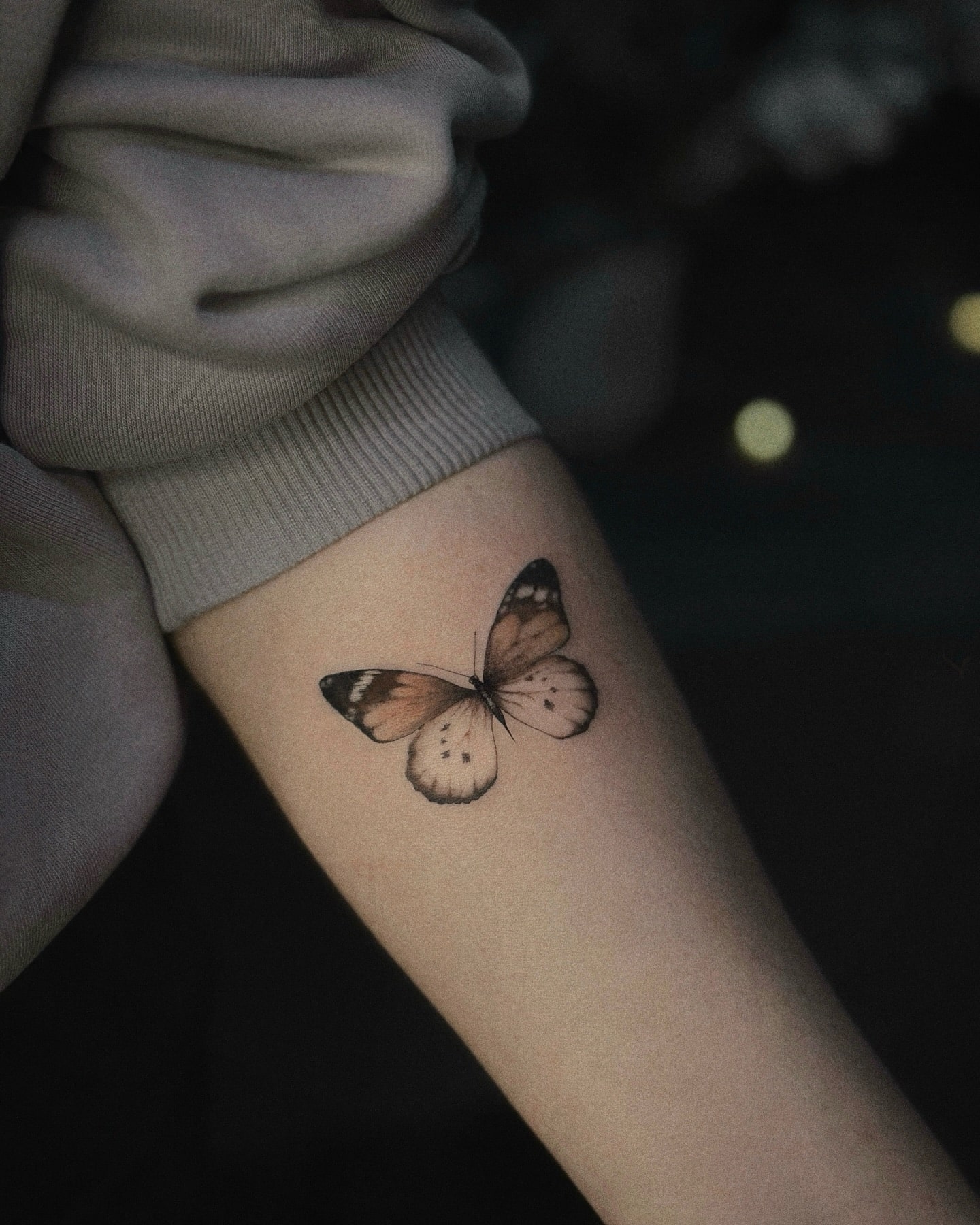 Realistic soft colored butterfly tattoo forearm in orange and cream