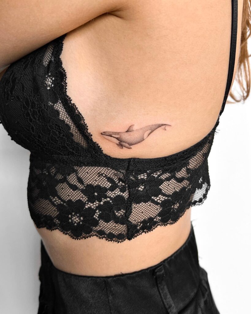 Realistic whale tattoo on the side rib, black and grey shaded for a subtle side view: whale's elegance