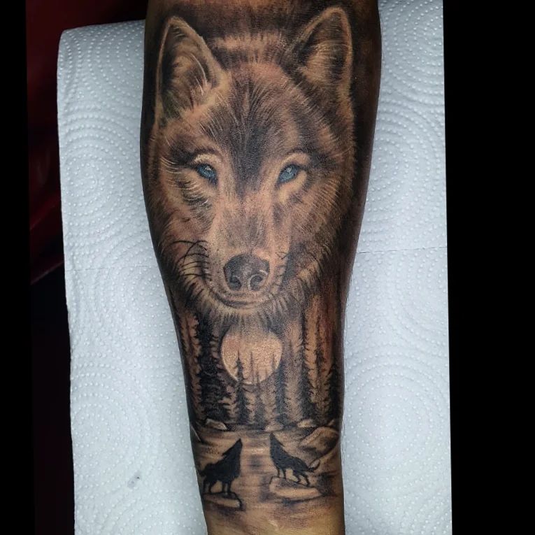 Realistic wolf tattoo with blue eyes on forearm piercing gaze in ink