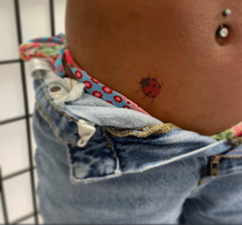 Red and Black Small Feminine Side Waist Ladybug Tattoo A Flirty and Feminine Accent