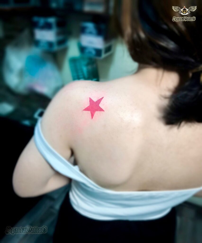 Red color filled single star tattoo on shoulder for females