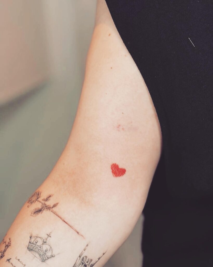 Red color filled small heart inner bicep tattoo for women vibrant and feminine