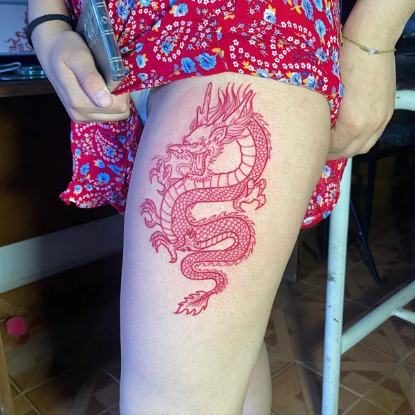 Red dragon tattoo on thigh