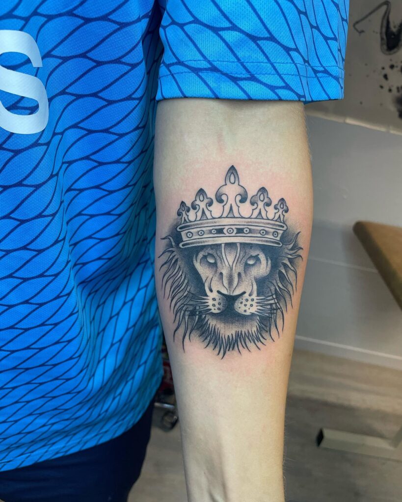 Remarkable lion face tattoo with crown design for men: regal forearm