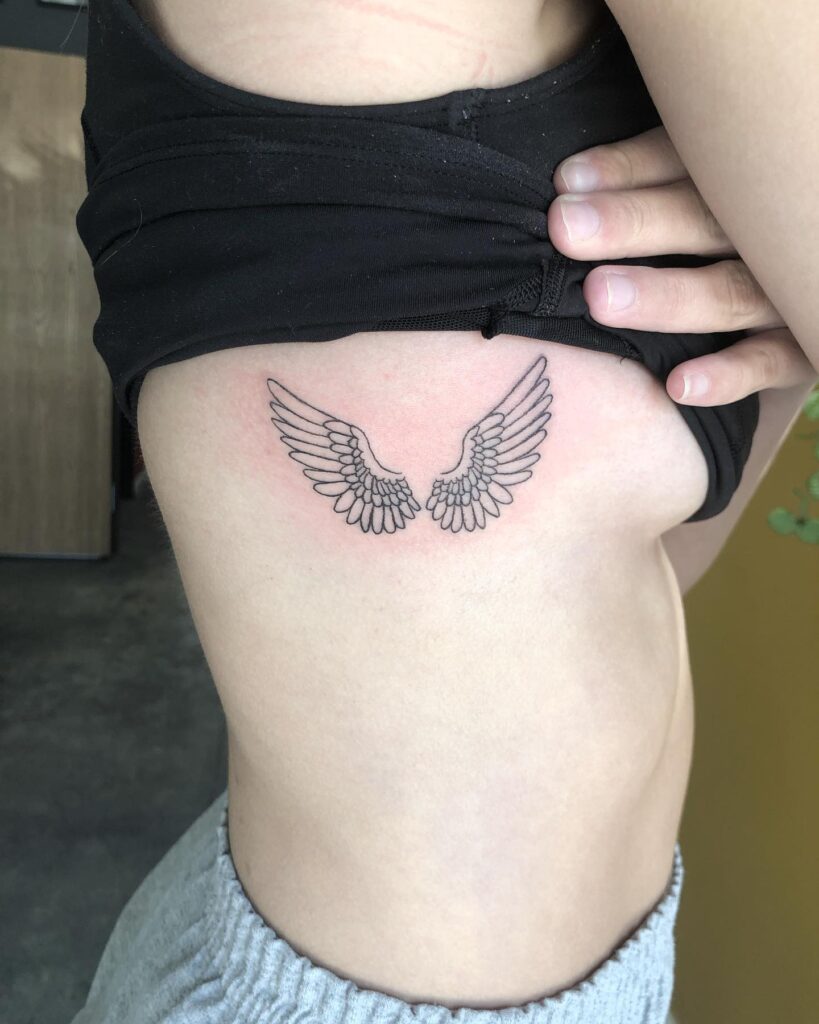 Rib wings fineline tattoo adding a touch of flight and freedom winged elegance