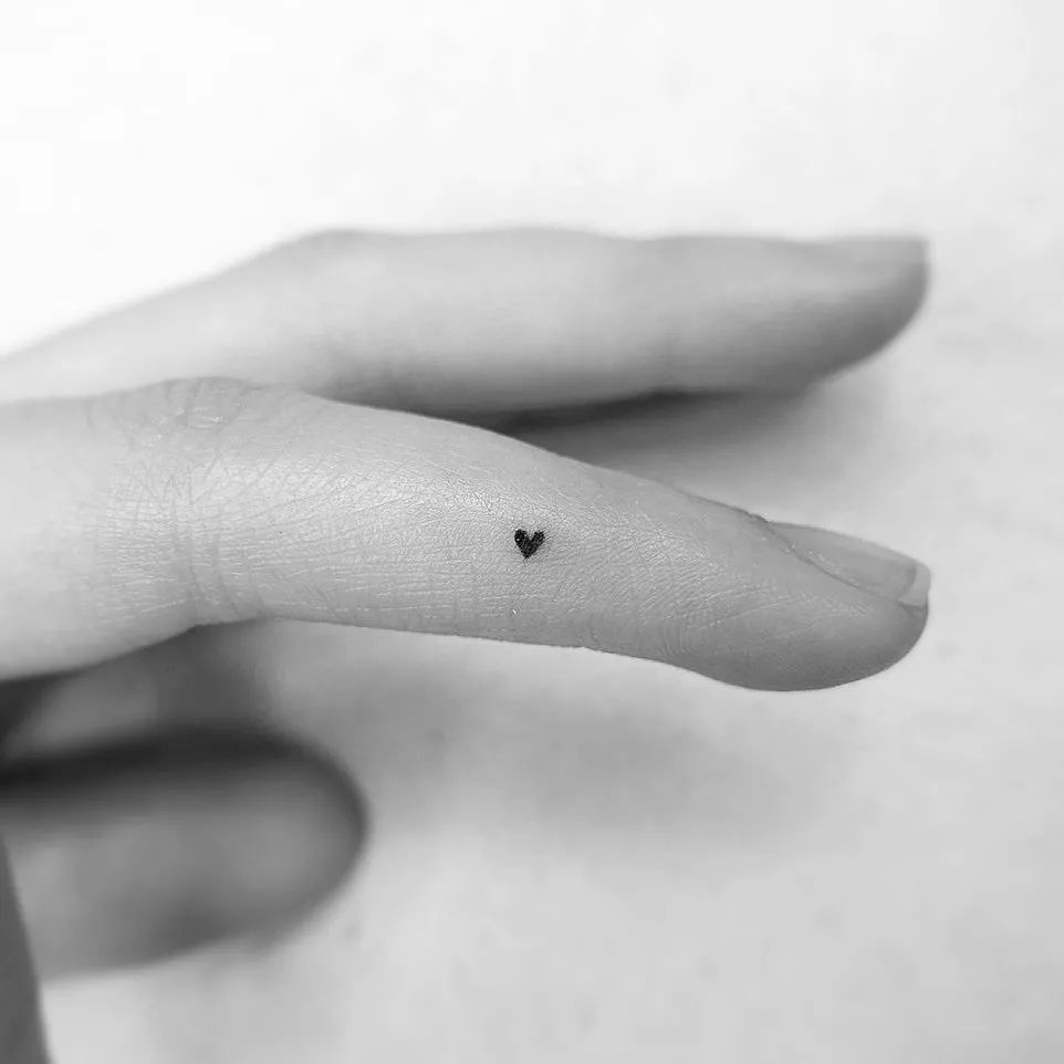 Ring-finger love small black filled heart tattoo