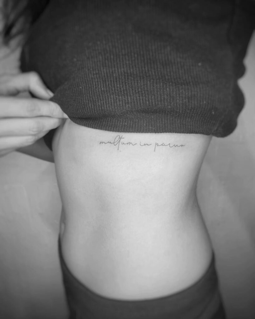 Script lettering tattoo on the side of the rib for women-"multum in parvo" elegance