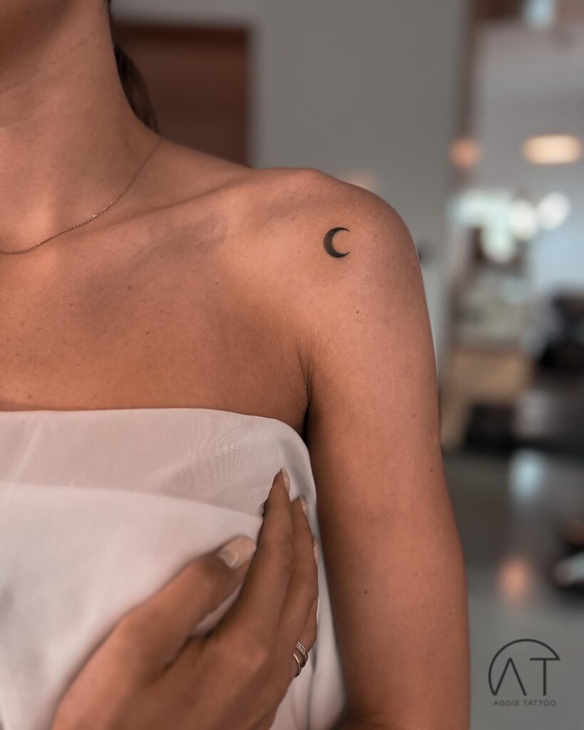 Tiny crescent moon tattoo on the front shoulder