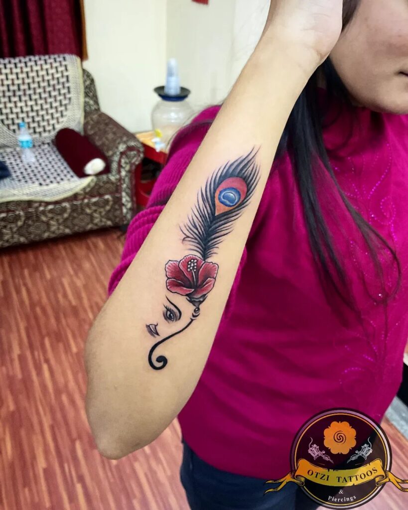 Side Peacock Feather, Ganesh, and Hibiscus Wrist Tattoo Idea for Females : Multisymbolic Ink