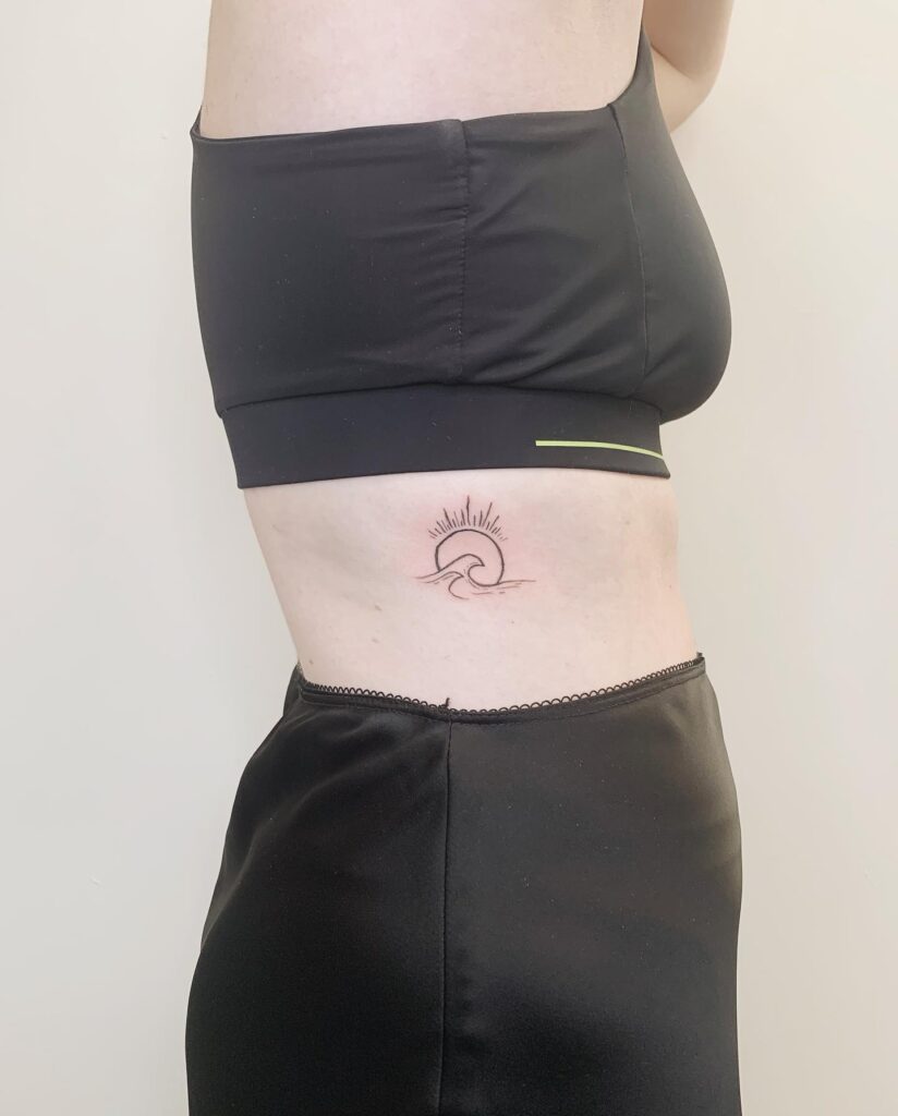 Side stomach sun and wave tattoo subtle sunshine