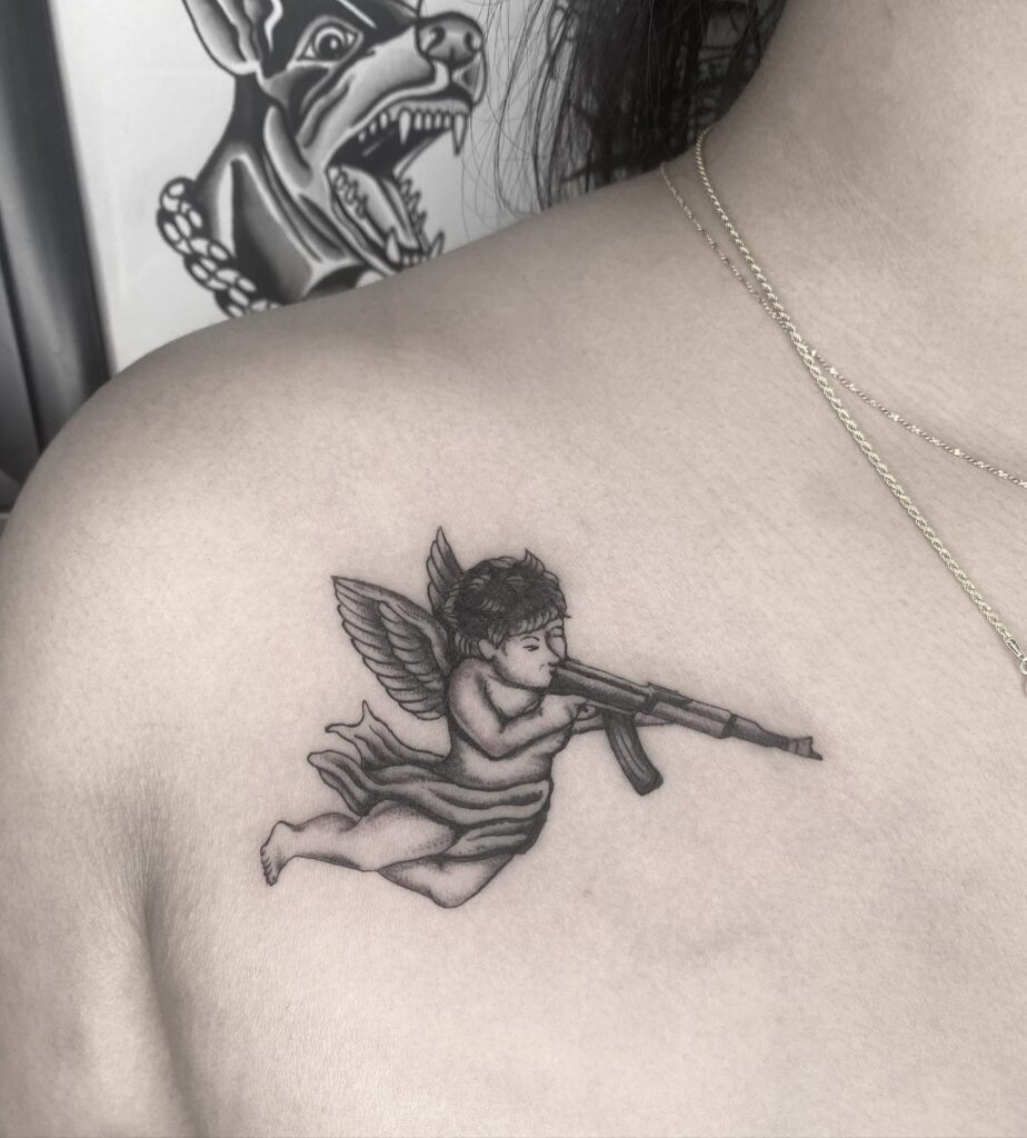 Side View Baby Angel with Gun Tattoo on the Collarbone: Heavenly Protector