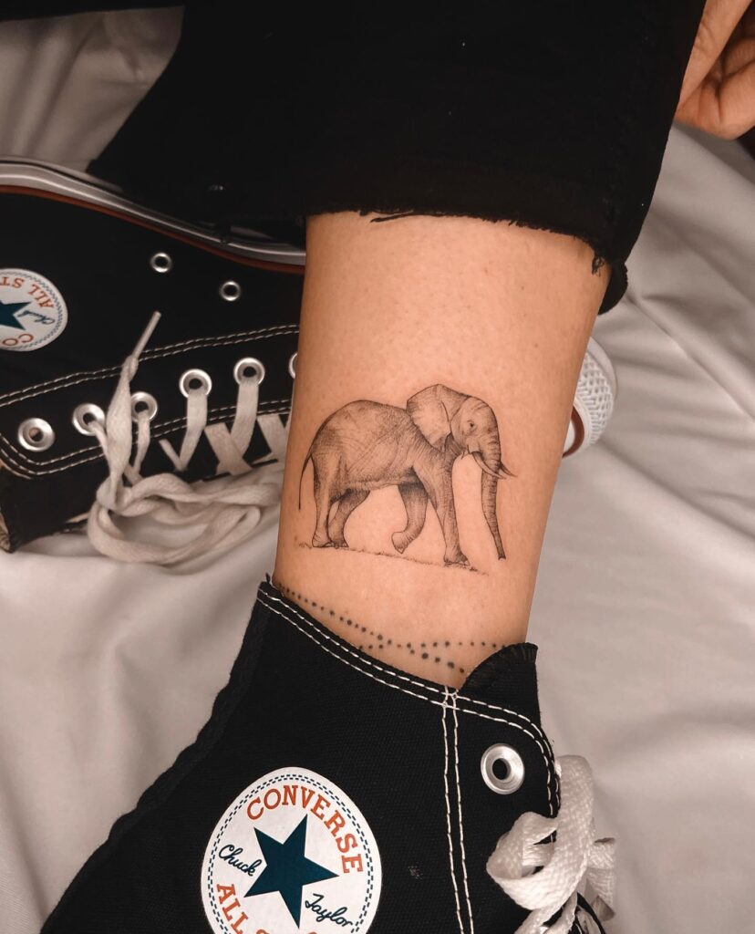 Side view of cute family above the ankle: delicate elephant parade tattoo design