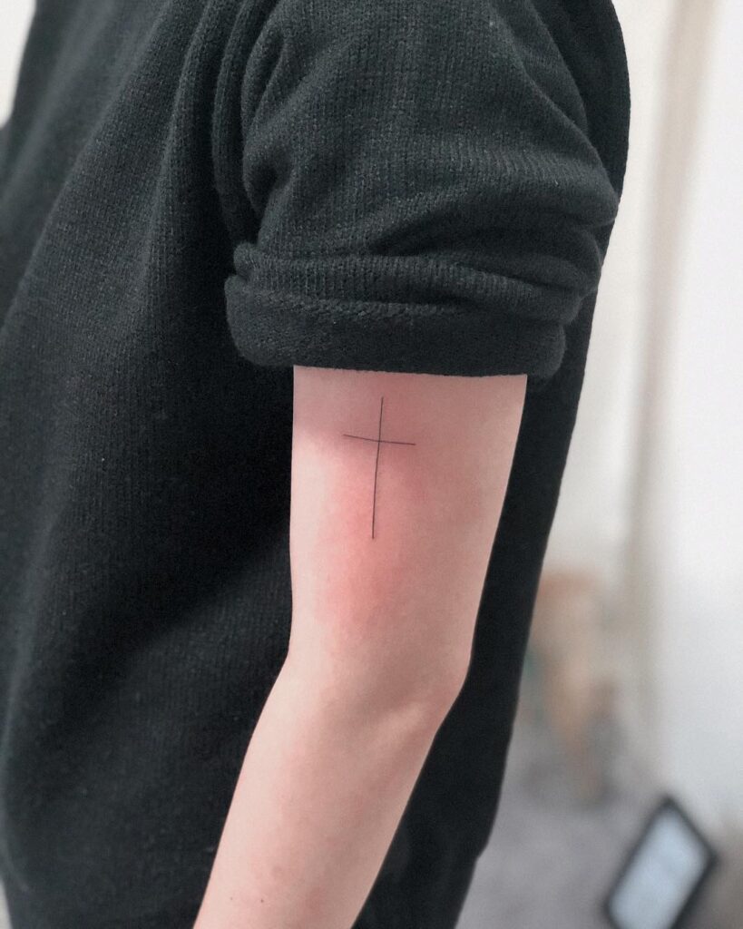 Simple and chic above elbow cross tattoo for men