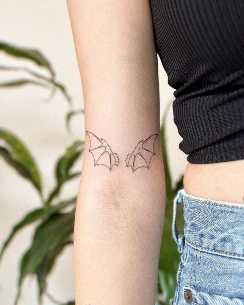 Simple and stylish outline wing tattoo above elbow