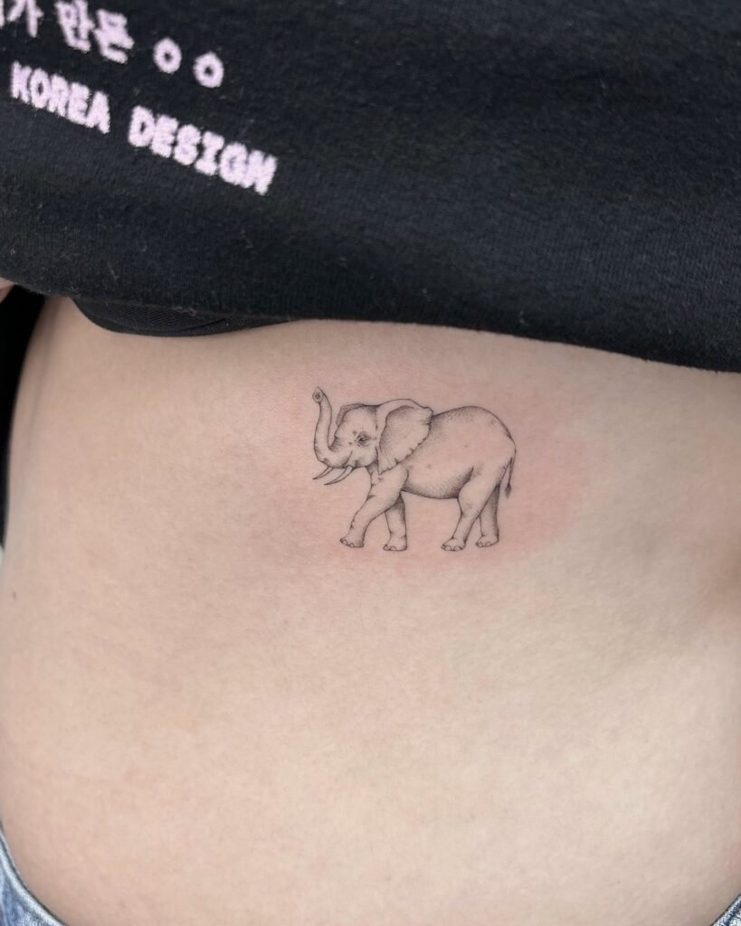 Simple baby elephant rib tattoo with elephant trunk up, a fineline tattoo on a larger canvas, side view tiny marvel