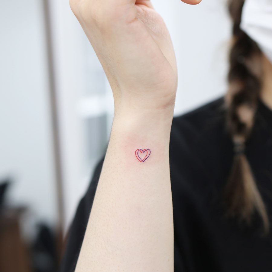 Simple double outline hearts small outer wrist tattoo in red and purple