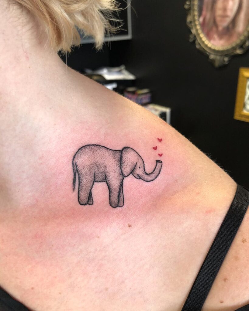 Simple elephant shoulder tattoo with trunk forming small red hearts, black and grey artistry love trunk