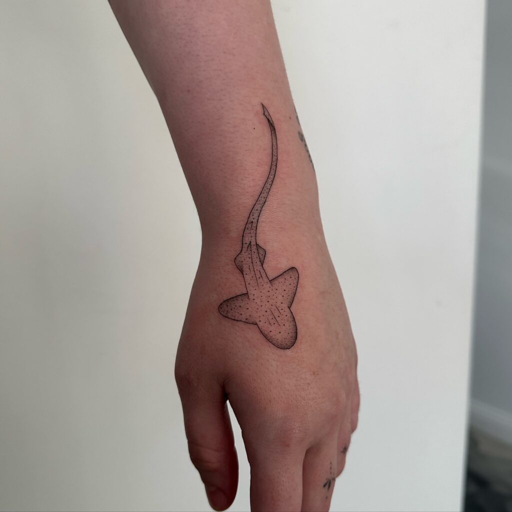 Simple ocean shark tattoo on the hand, top view, black outline with grey shading oceanic elegance