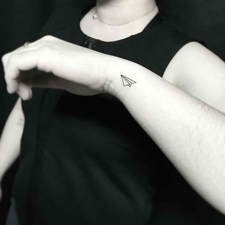 Simple Paper Airplane Tattoo on Wrist Symbolizing Freedom Adventure and Creativity