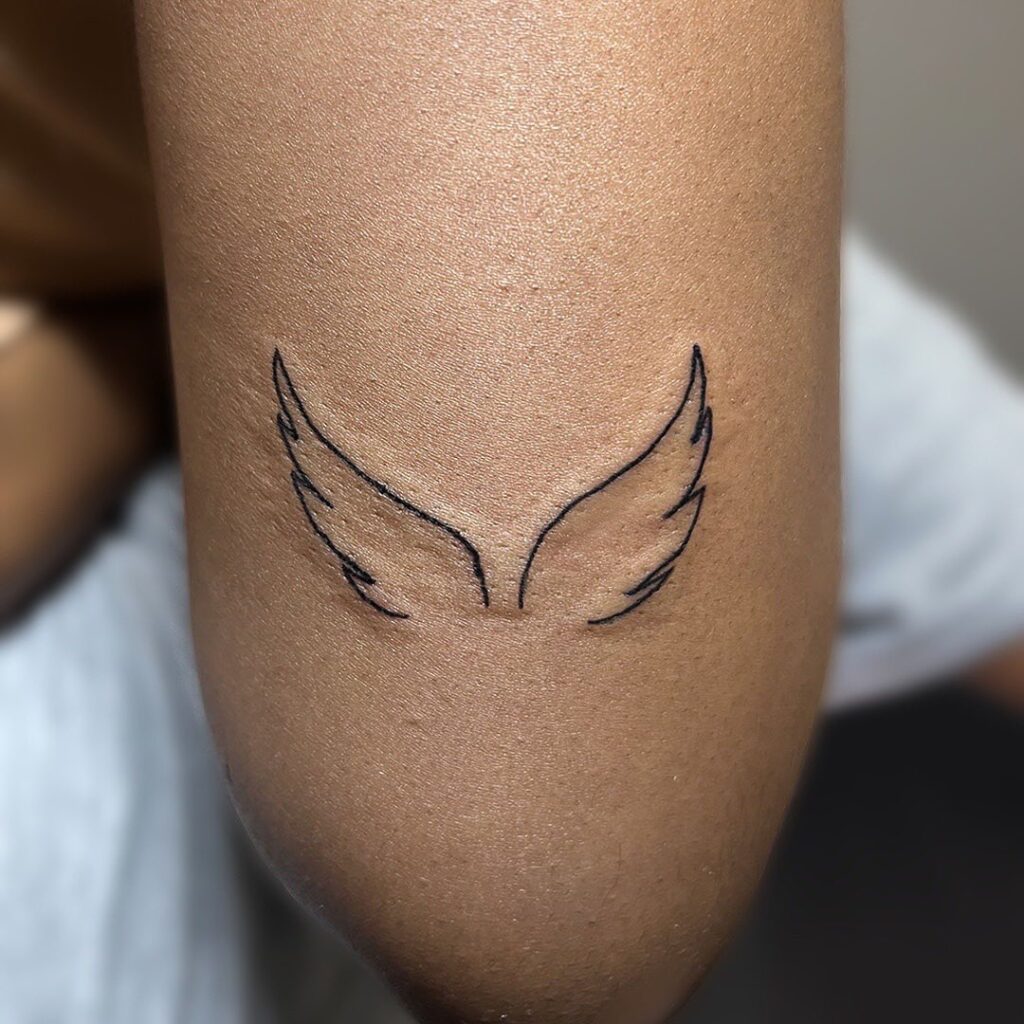 Simple & stylish minimal wing tattoo above elbow
