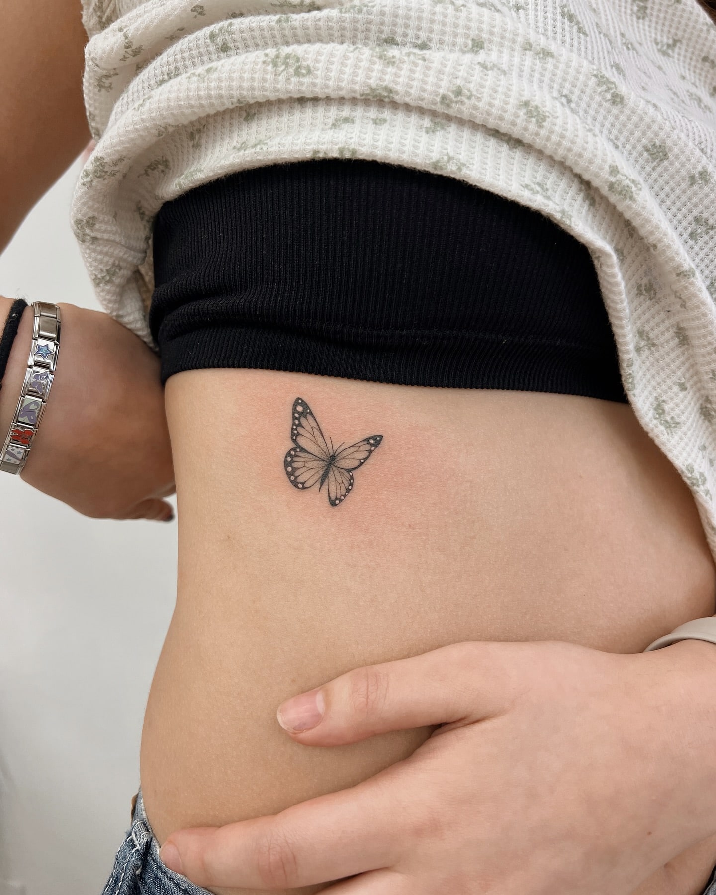 Single butterfly tattoo above hip with soft shading and delicate linework