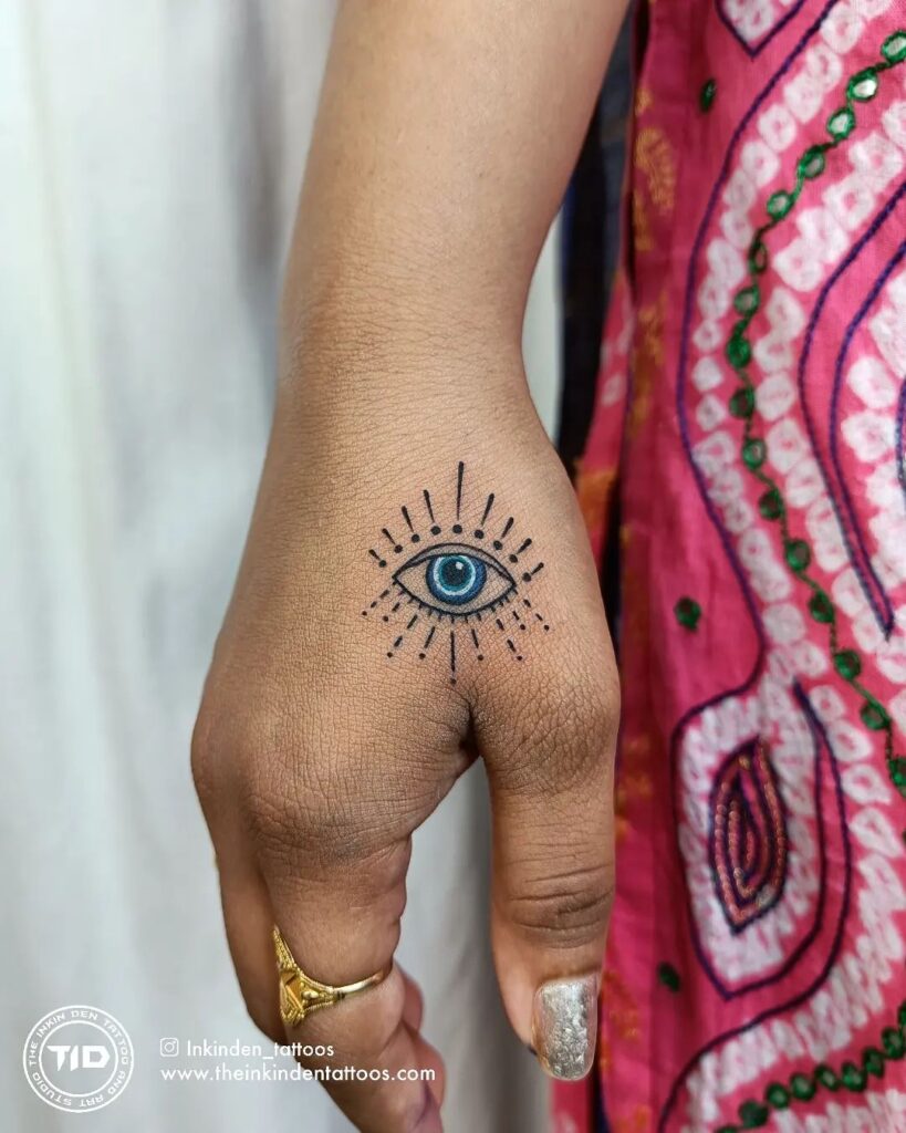 Sky Blue Evil Eye Tattoo with a Splash of Color on the Hand: Colorful Guardian