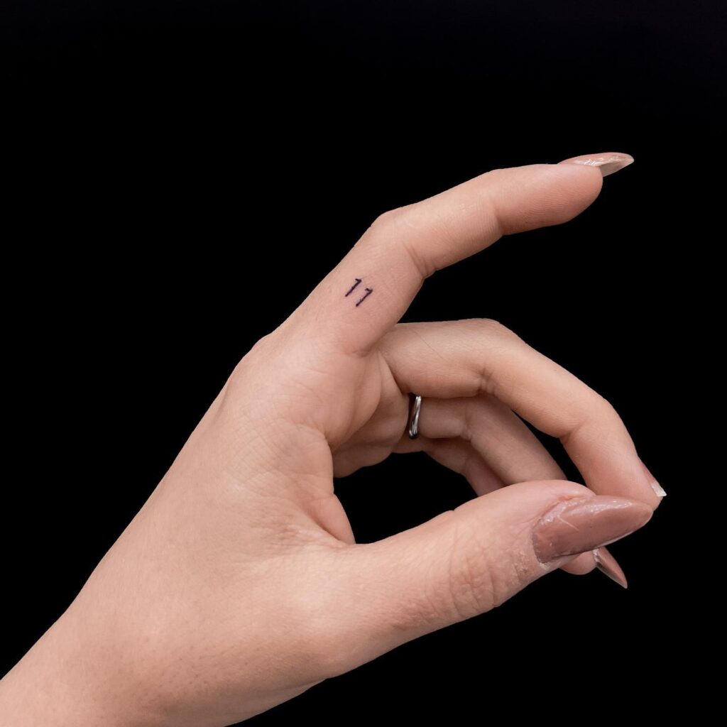 Small 11 Number Tattoo on the Side of the Finger a Minimalist Numeric Statement: Numerical Charm
