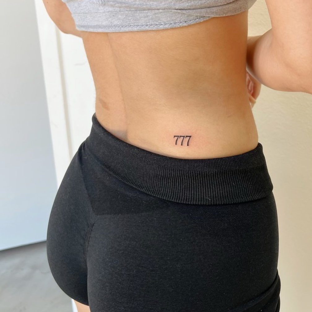 Small 777 Tattoo on the Side of the Lower Back: Feminine Charm 
