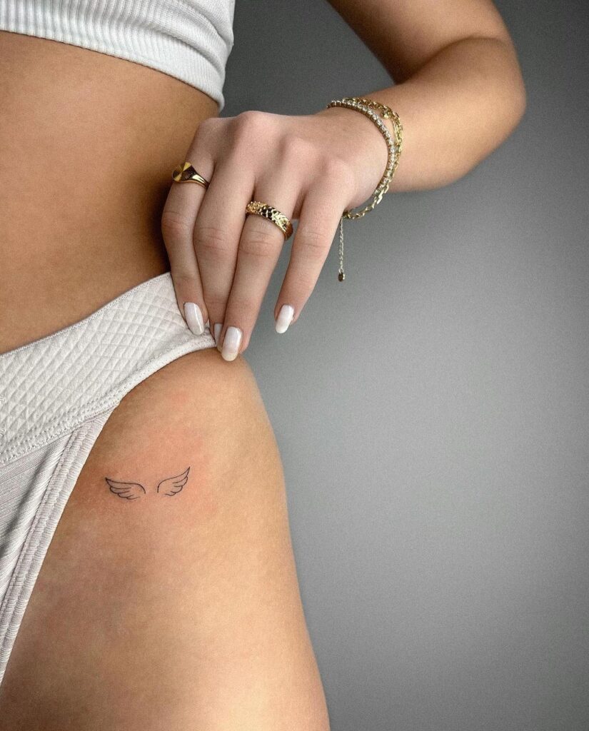 Small and cute angel wing outline tattoo on the hip an elegant accent angel's embrace