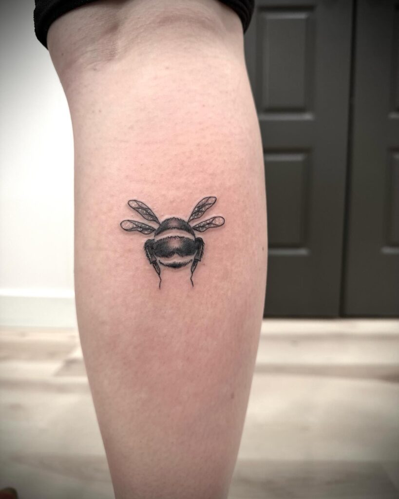 Small Bee Tattoo on the Calf in Chic Black and Grey: Buzzing Elegance 