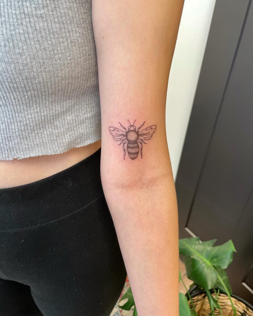 Small Black and Grey Bee Tattoo Above the Elbow: Nature's Worker