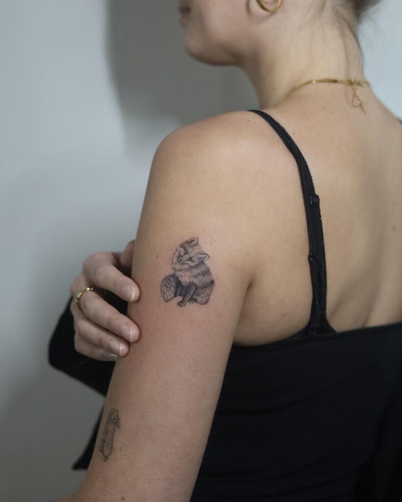 Small Black and Grey Fox Tattoo on the Upper Arm: Head Tilted Elegance
