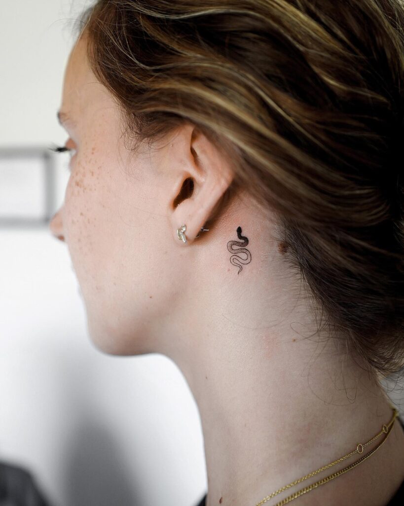 Small Black Snake Behind Ear Tattoo Sleek Modern and Mysterious