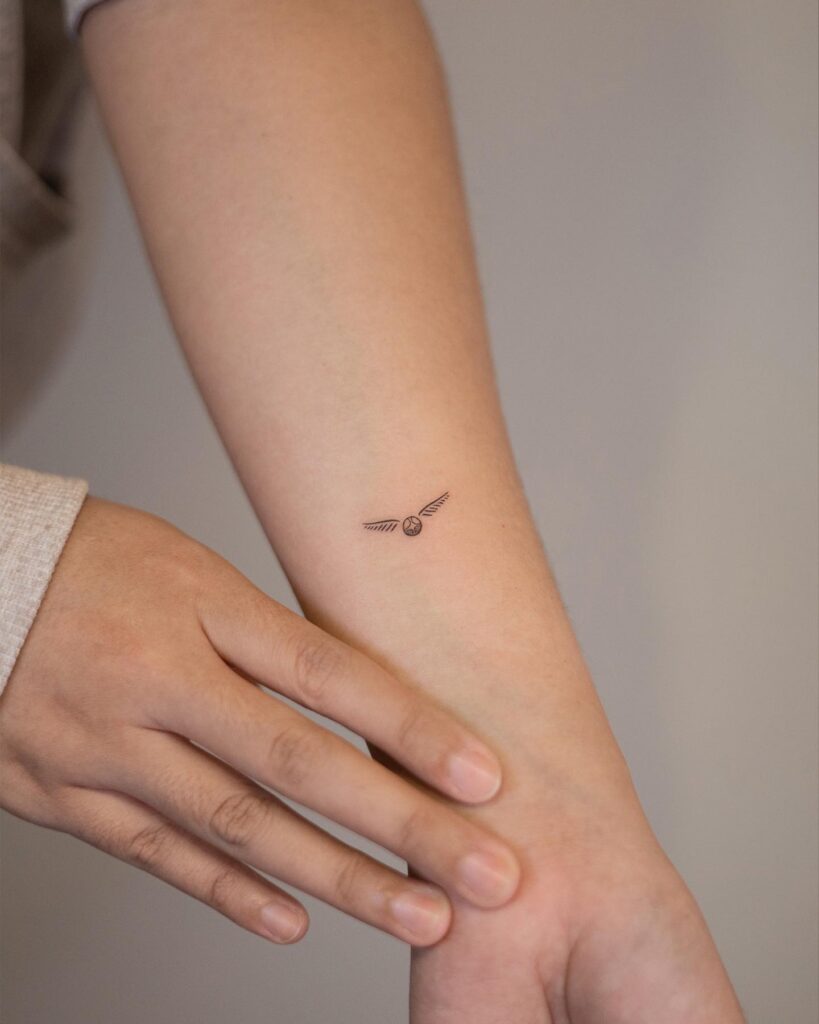 Small classy women's unique lower arm golden snitch tattoo