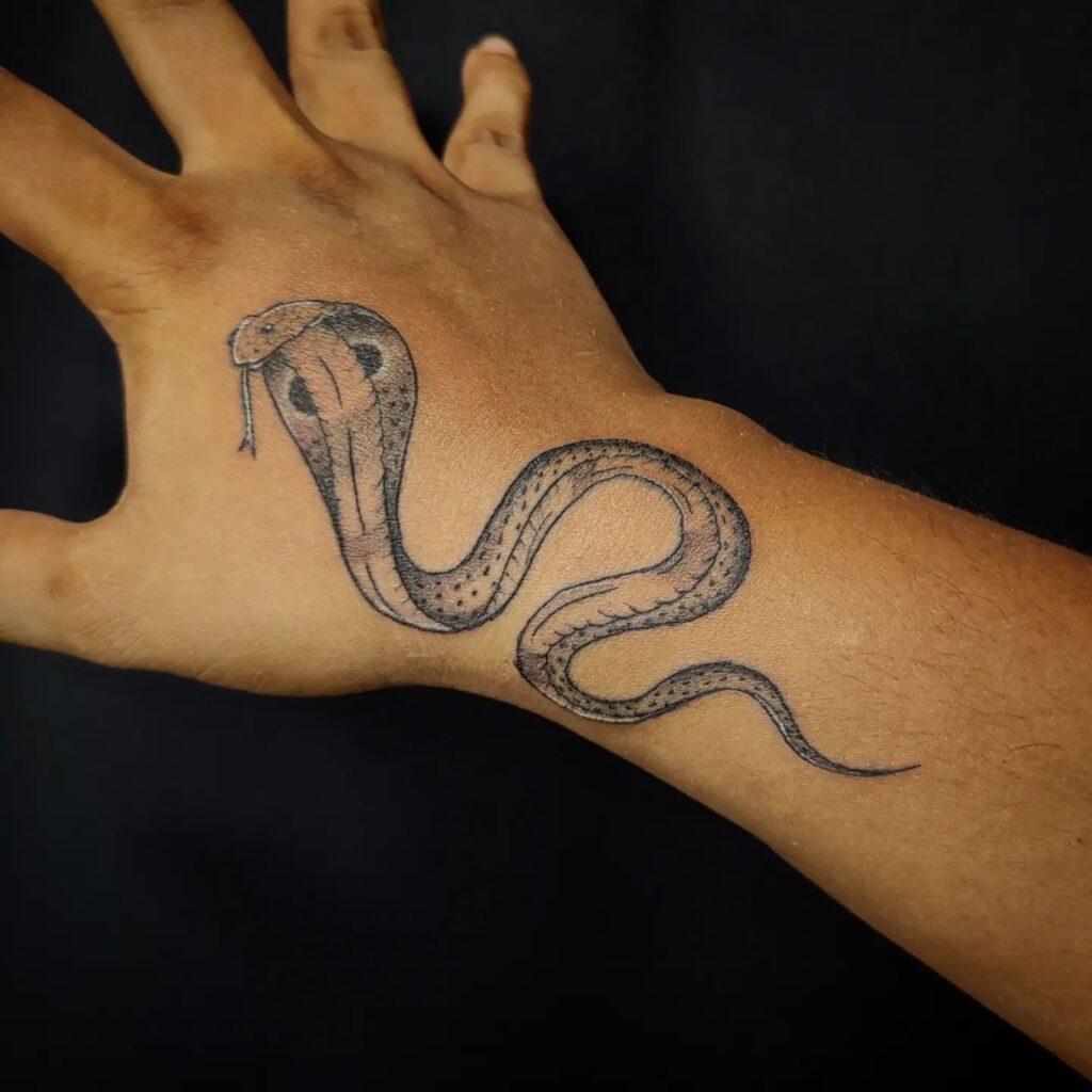 Small cobra tattoo on the outer hand with tongue out: handcrafted menace