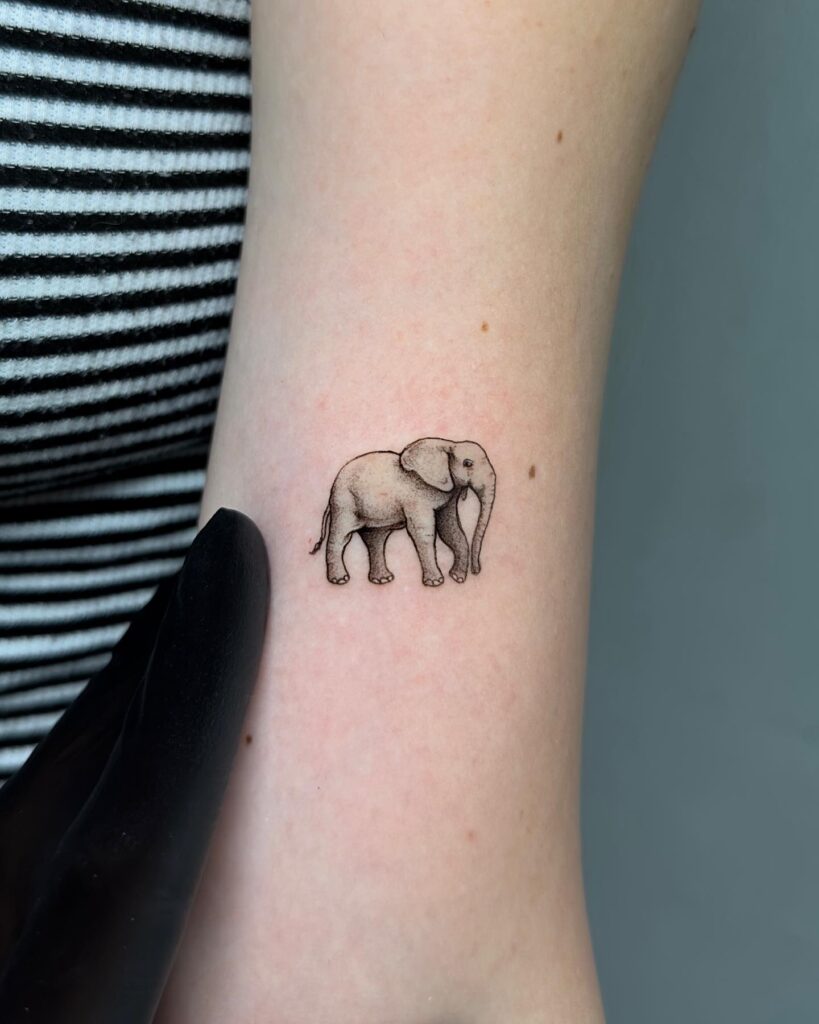Small cute side view elephant tattoo on arm: above elbow delight