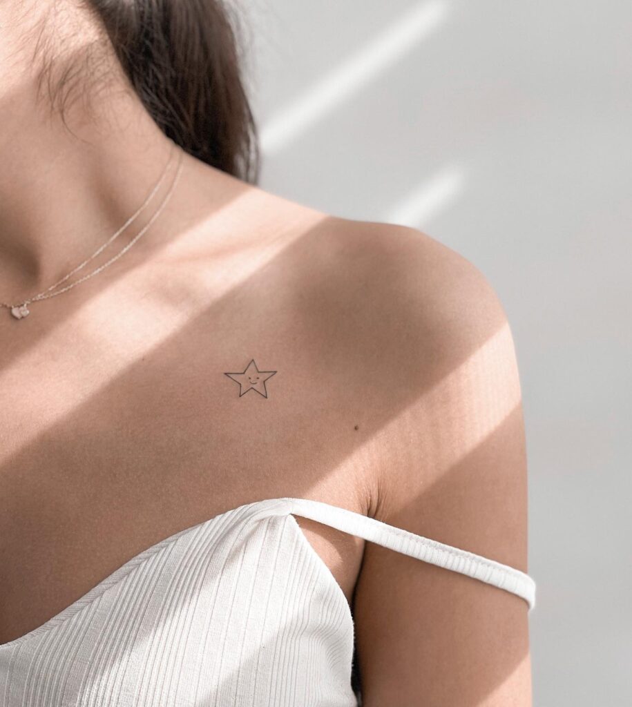 Small cute tattoo on the collarbone: star embraced smiley