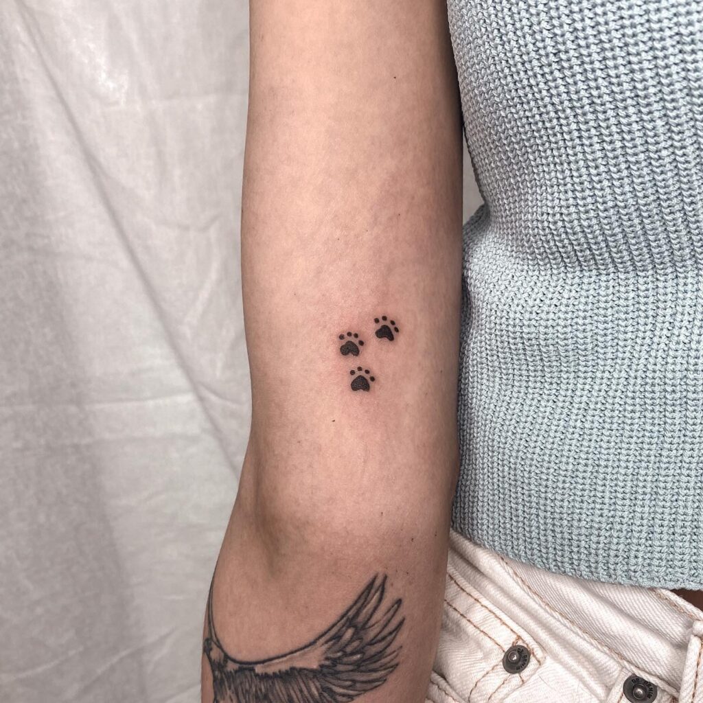 Small Dog Paw Tattoo on the Inner Arm for Females, Three Paws Filled with Black Color: Pawfect Trio