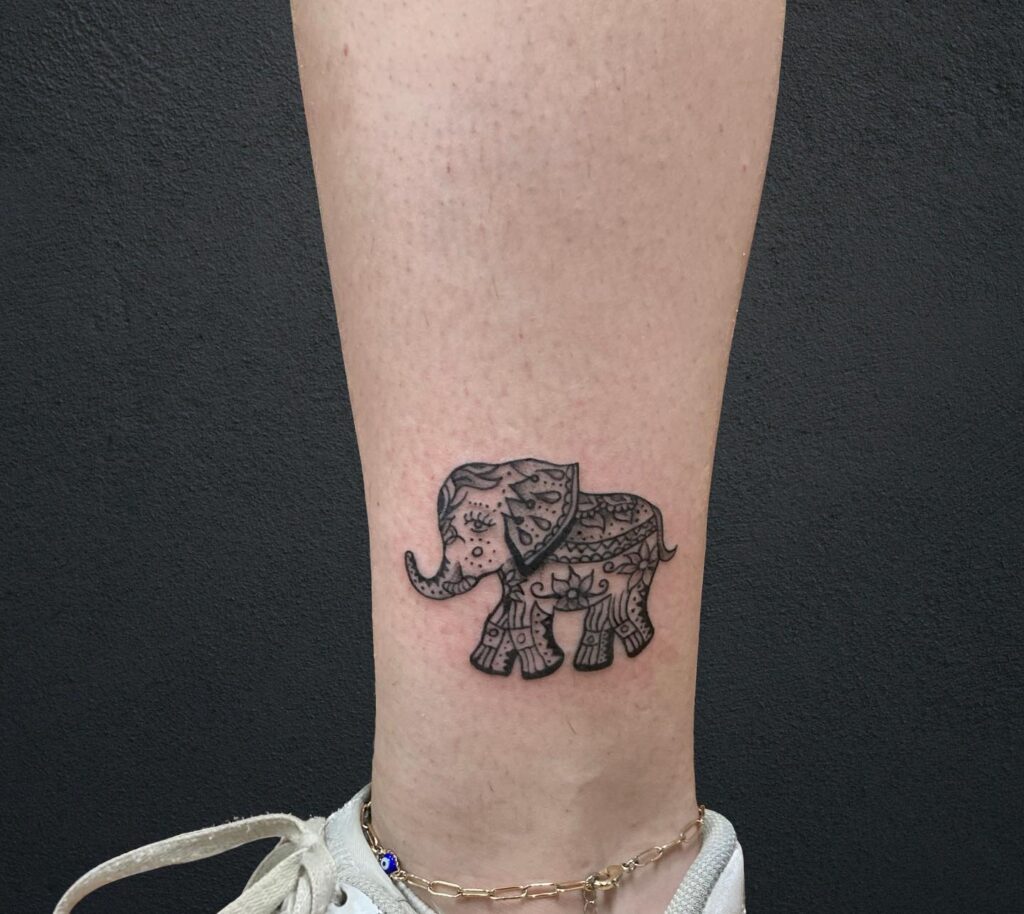 Small elephant tattoo above the ankle with mandala filling, a thin and elegant side view mandala whispers