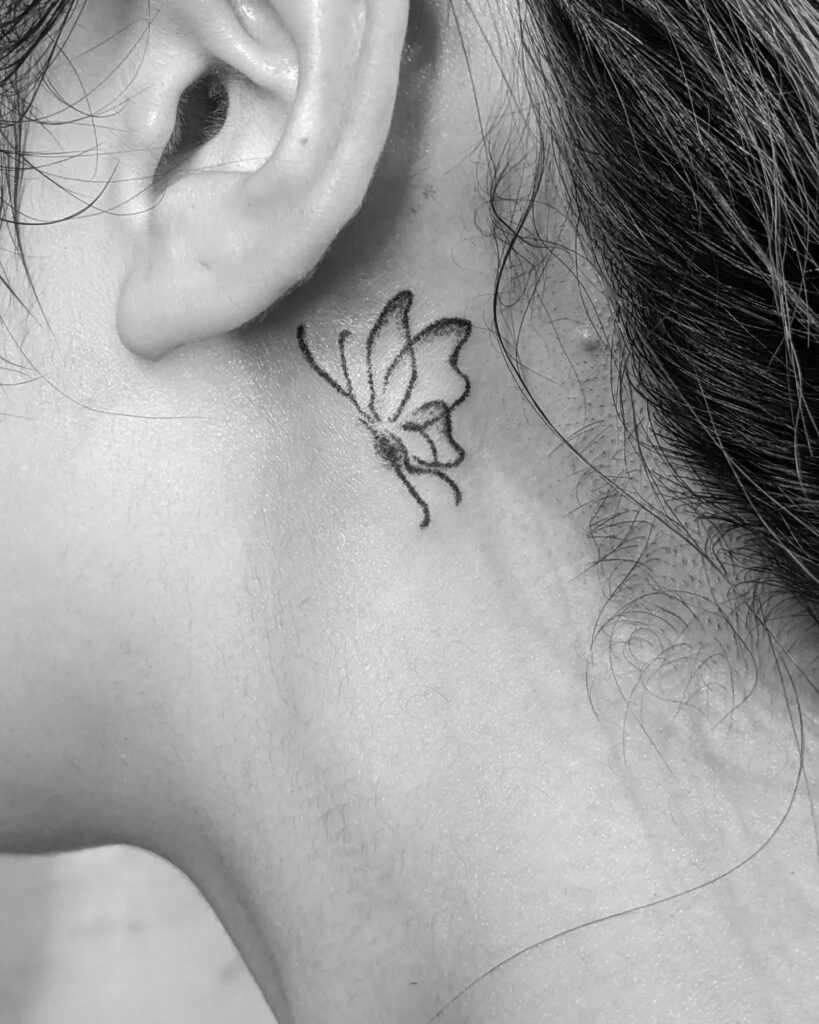 Small intricate outline butterfly tattoo behind the ear whispered elegance