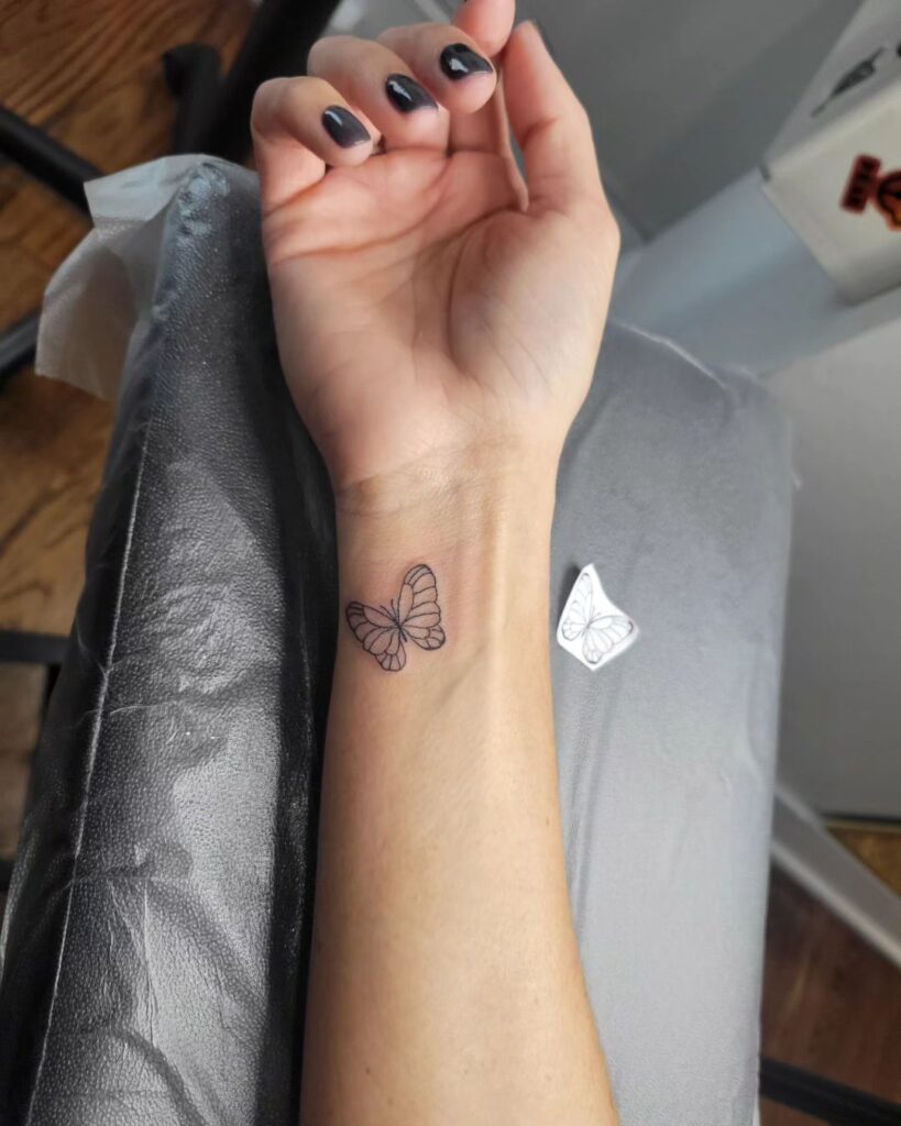 Small linework butterfly tattoo on wrist minimalist insect ink
