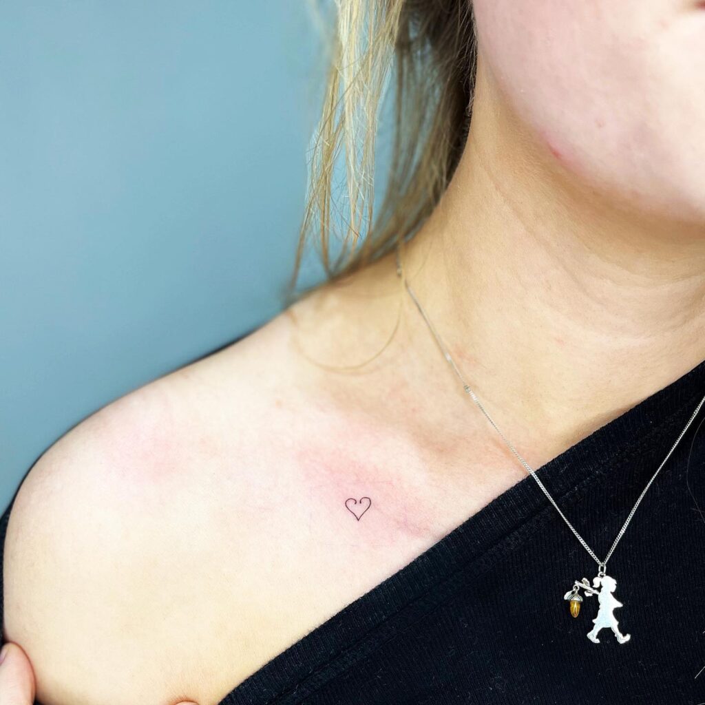 Small outline love heart on collarbone tattoo for a female