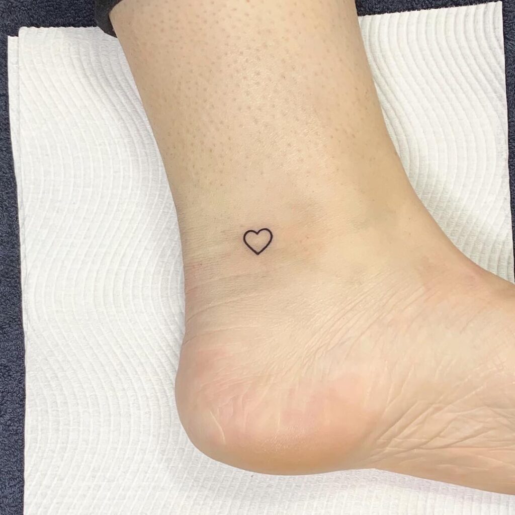 Small outline love heart tattoo near the ankle for a girl