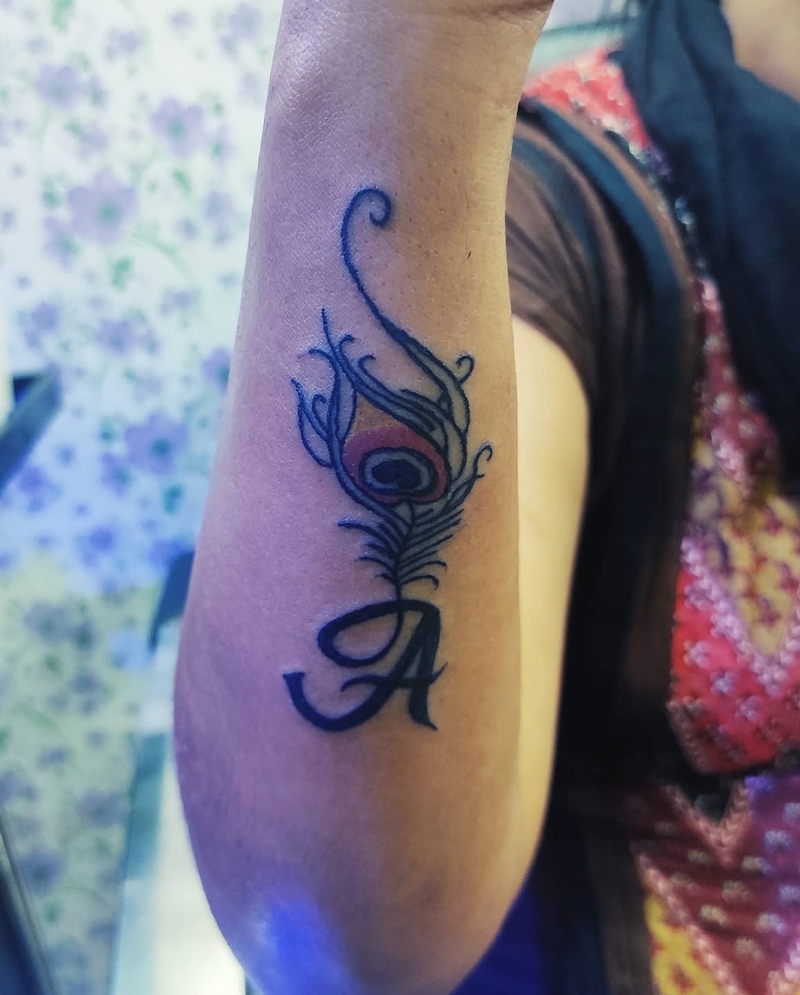 Small peacock feather tattoo on hand with big initials Small peacock feather tattoo on hand with big initials