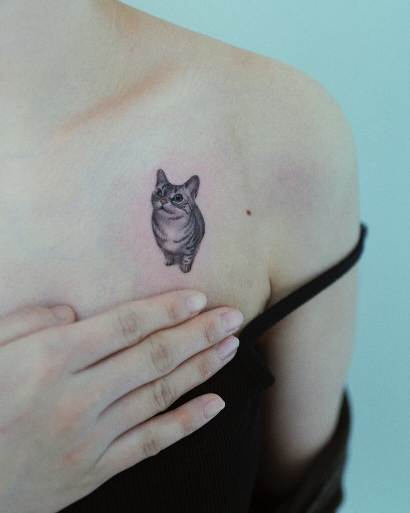 Small realistic tabby cat upper chest tattoo with expressive eyes