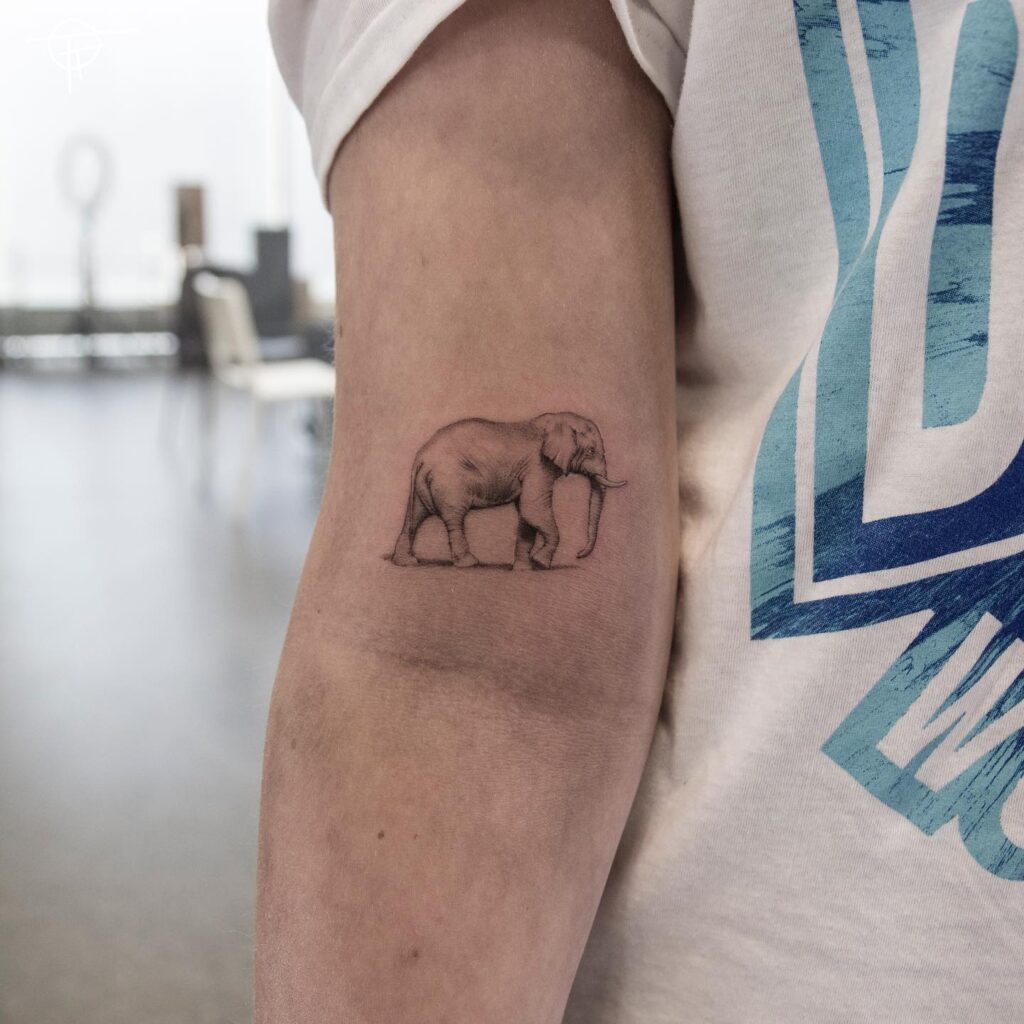 Small side view elephant tattoo in black ink: chic above elbow charm
