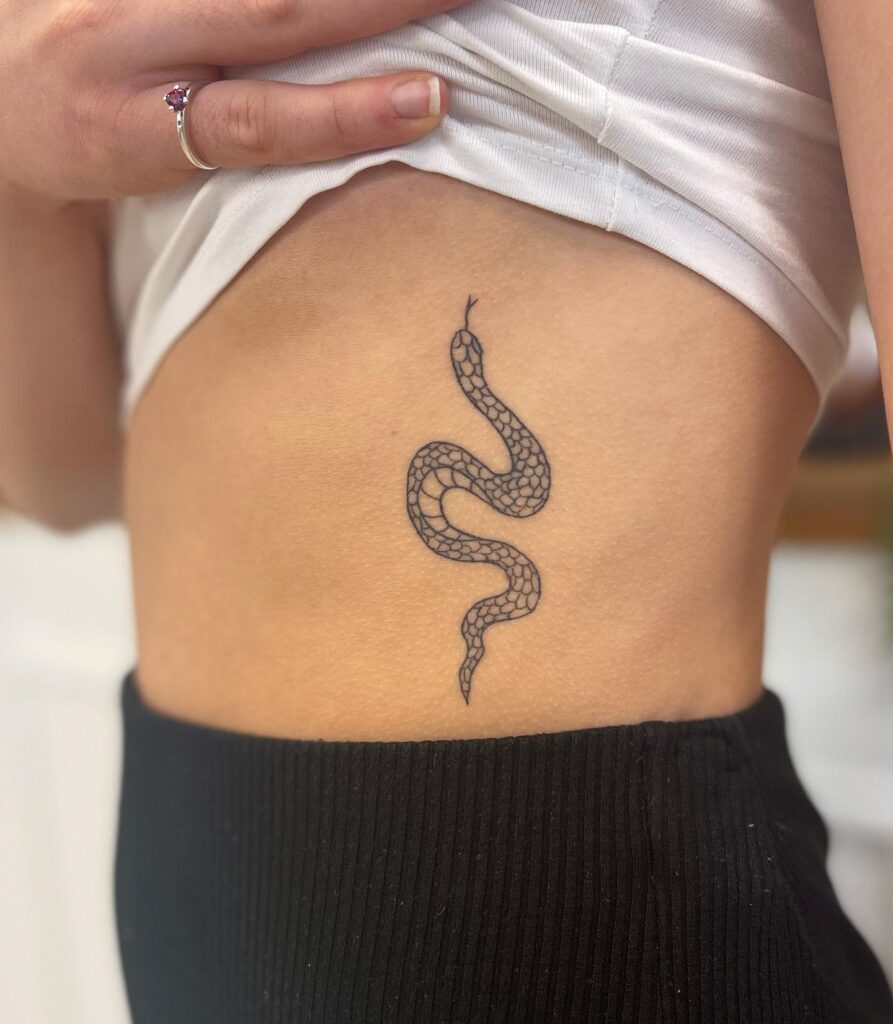 Snake tattoo on the rib, detailed and intricate with forked tongue and black ink: serpentine elegance
