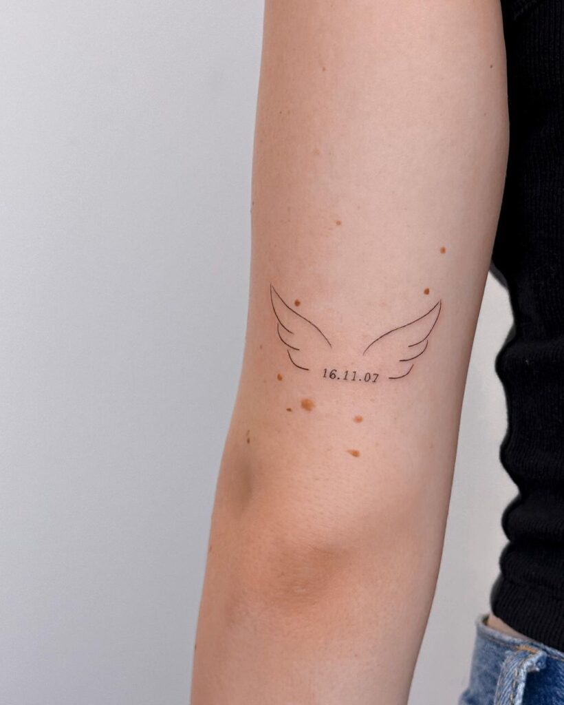 Special date fineline angel wings tattoo above elbow