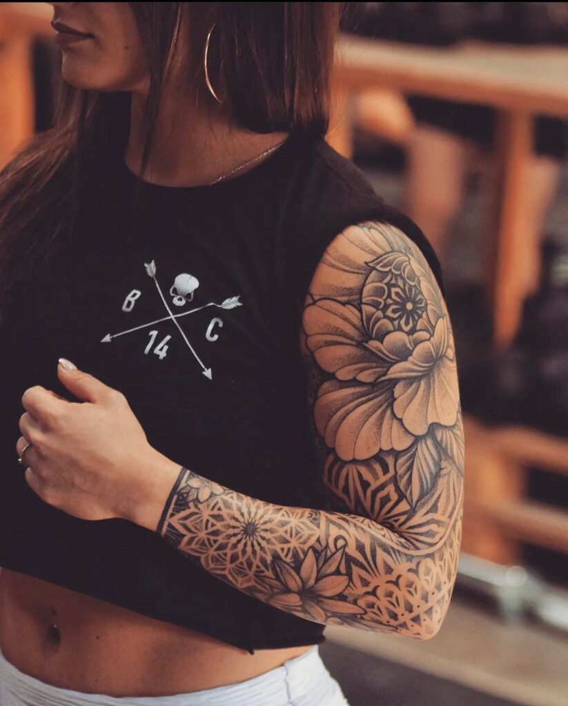 Strength and beauty mandala sleeve tattoo with flowers for a female bodybuilder